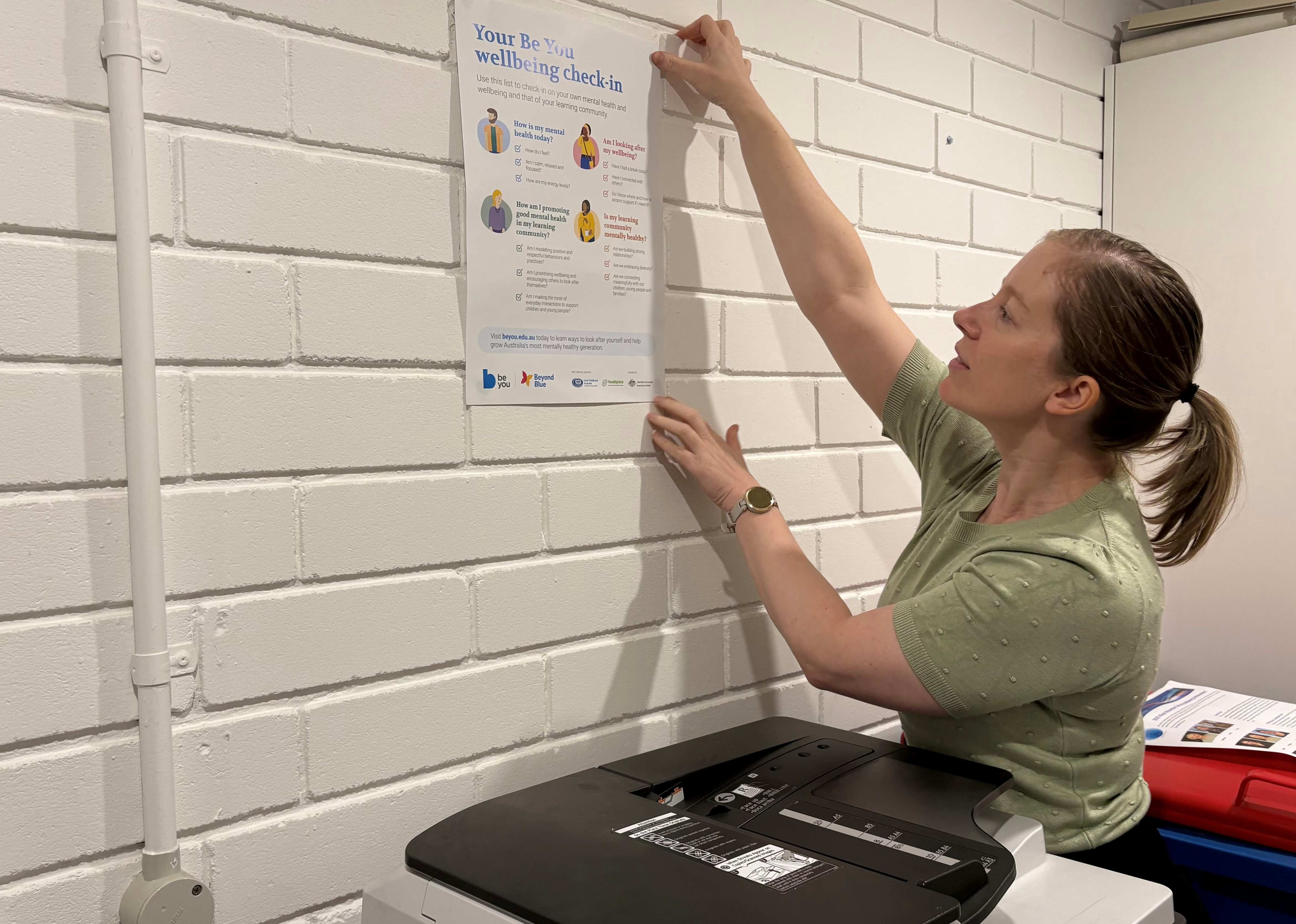 Dr Kayla Ball putting up a poster on a wall