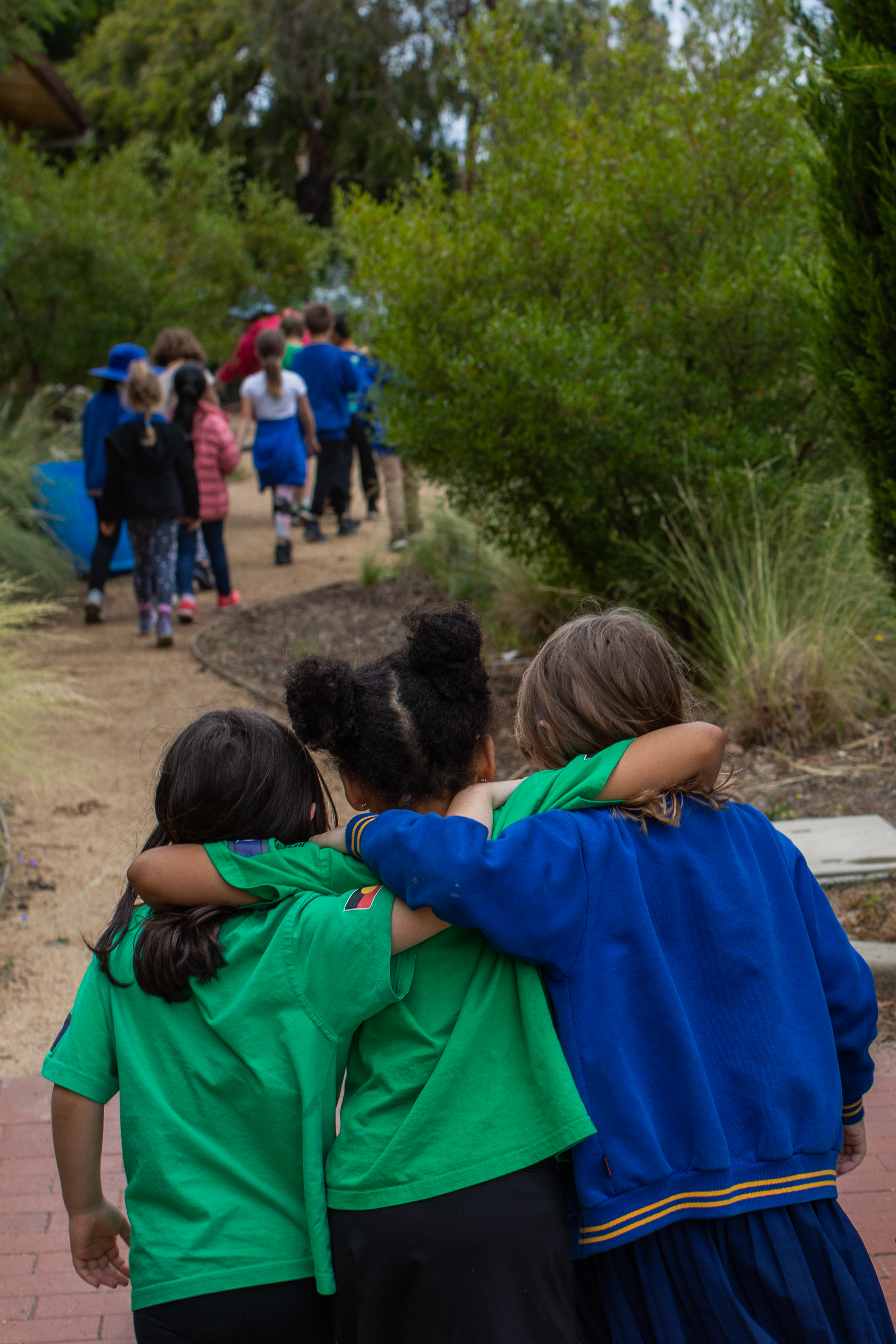 Three primary school students hugging