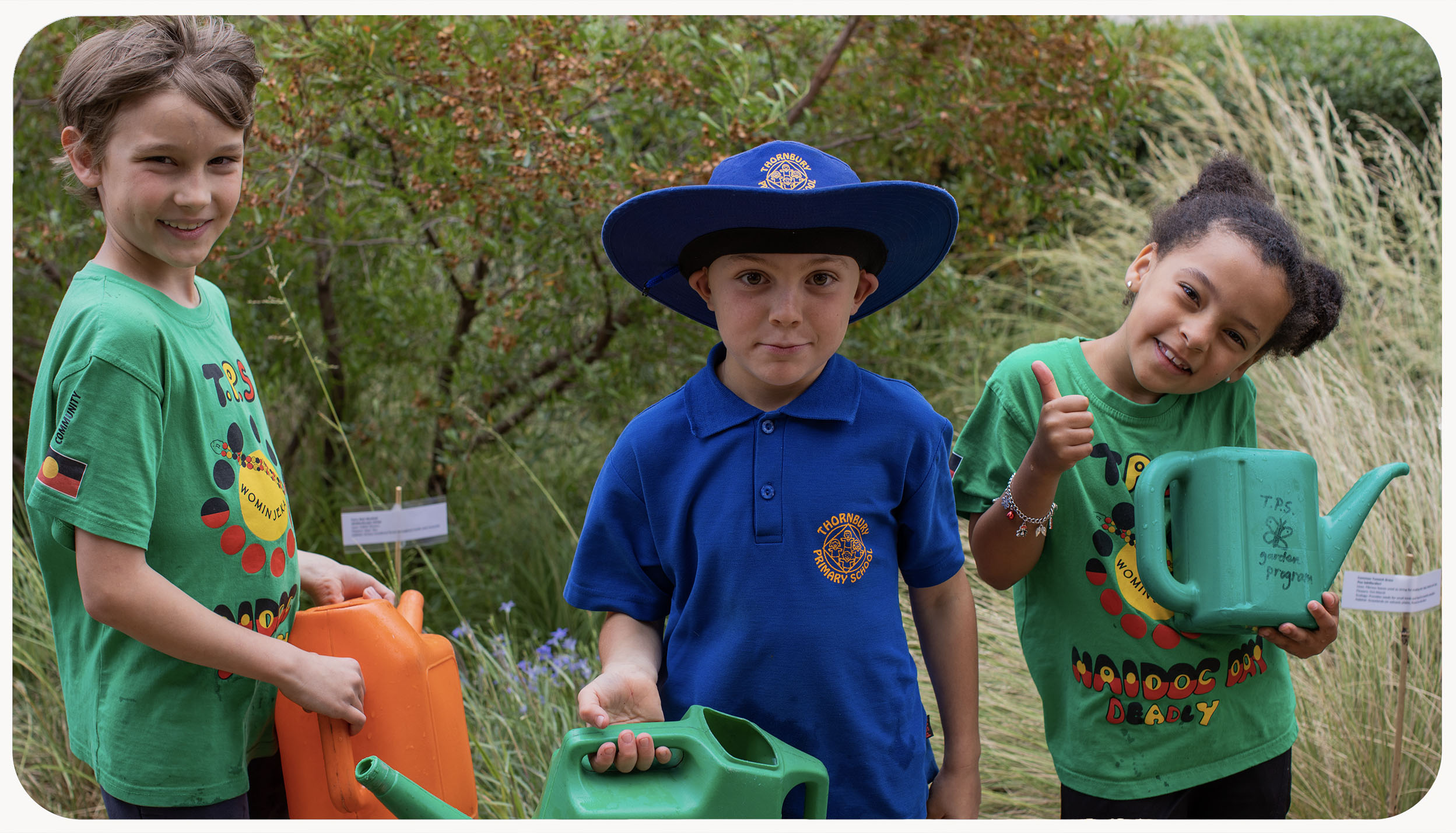 Three children holding watering cans 