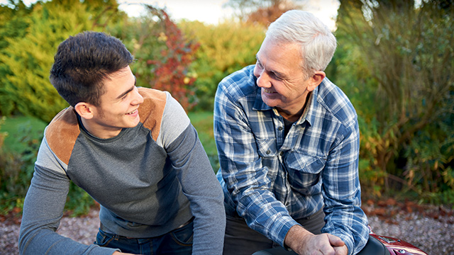 An adolescent and family member sitting together, smiling 