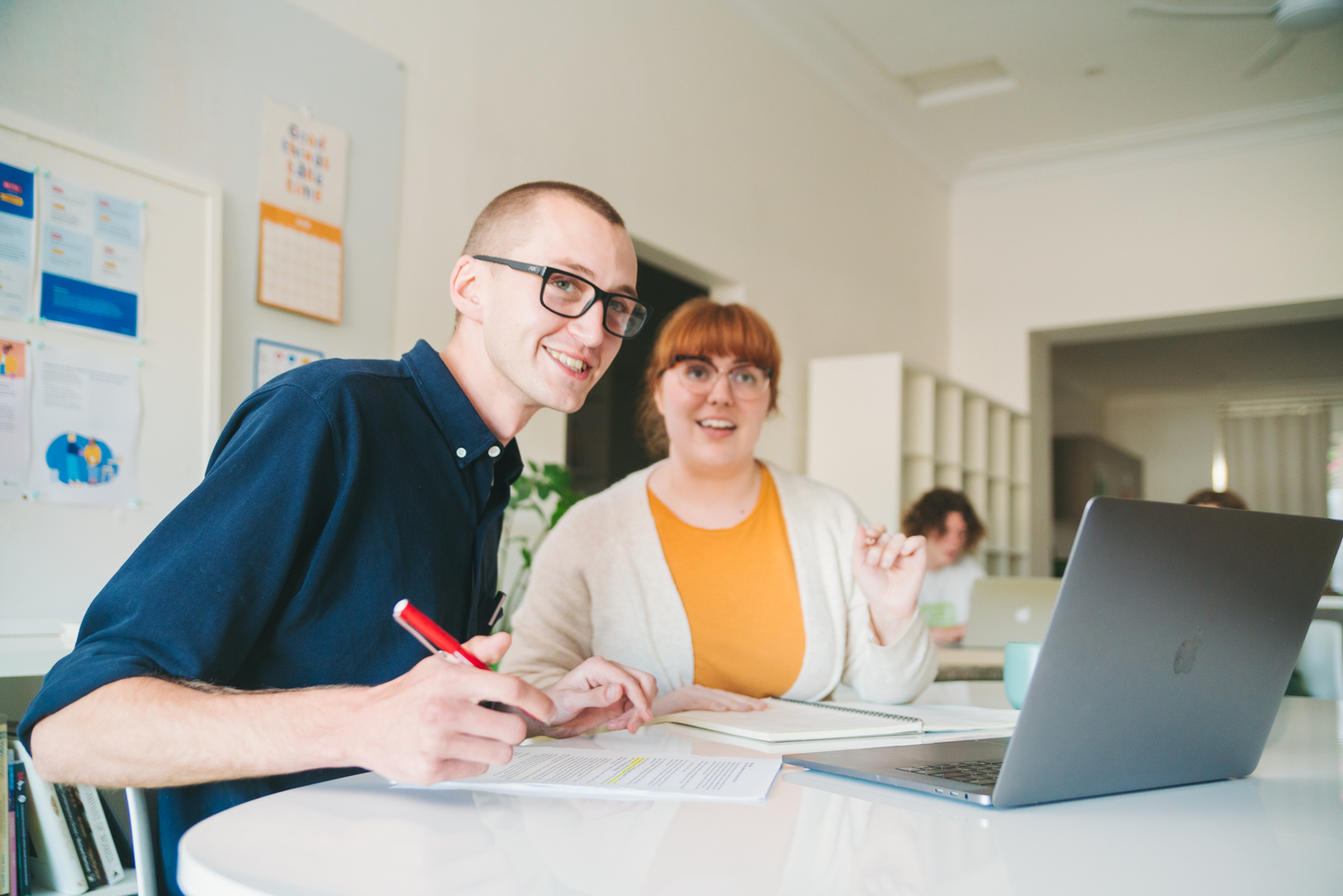 Two educators sitting at desk looking at camera.