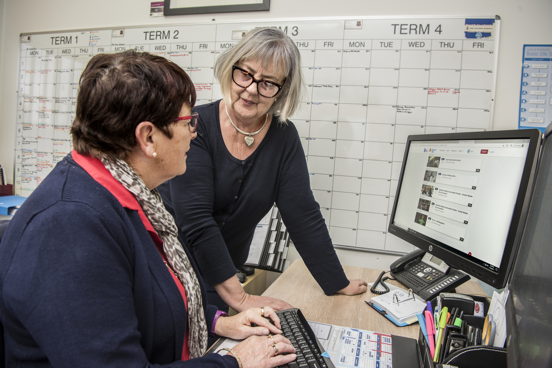 Two adults having a discussion while working at a computer