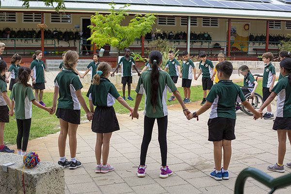 A group of children holding hands in a large circle