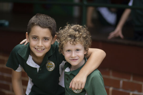 Two children with their arms around each other, smiling at the camera